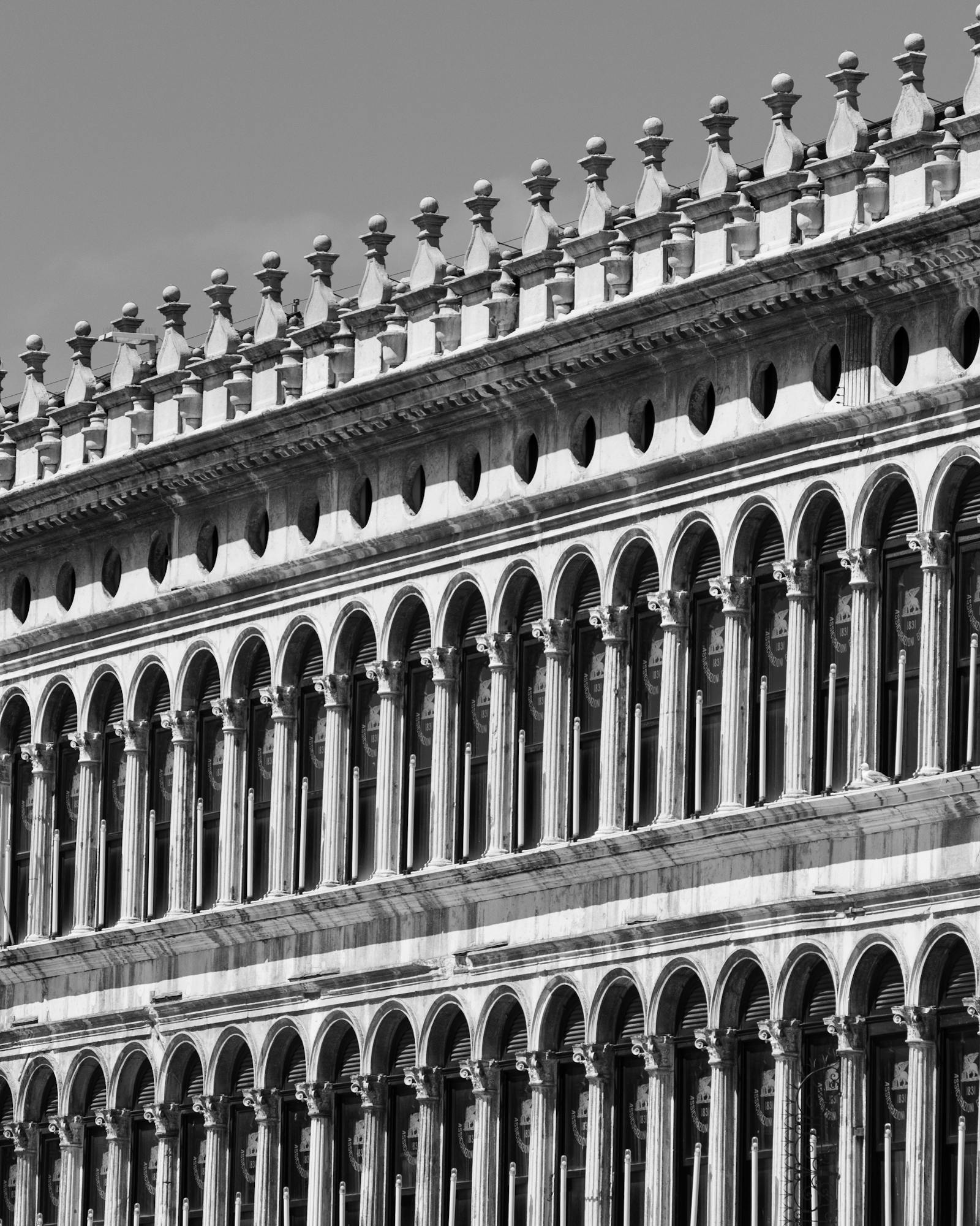 Black and white photo of the iconic arches of Procuratie Vecchie in Venice, Italy.