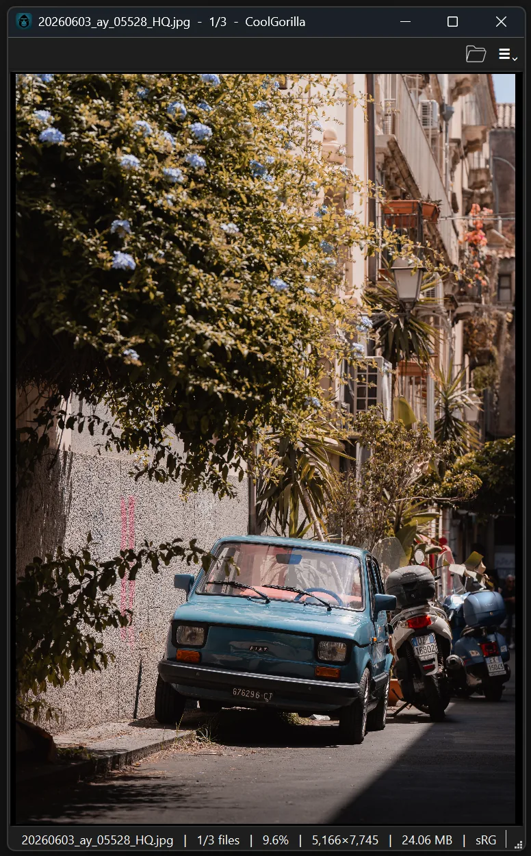 A narrow portrait CoolCroco window showing a blue car on a Sicilian street